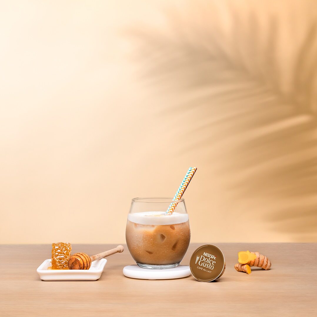 iced latte next to a coffee capsule